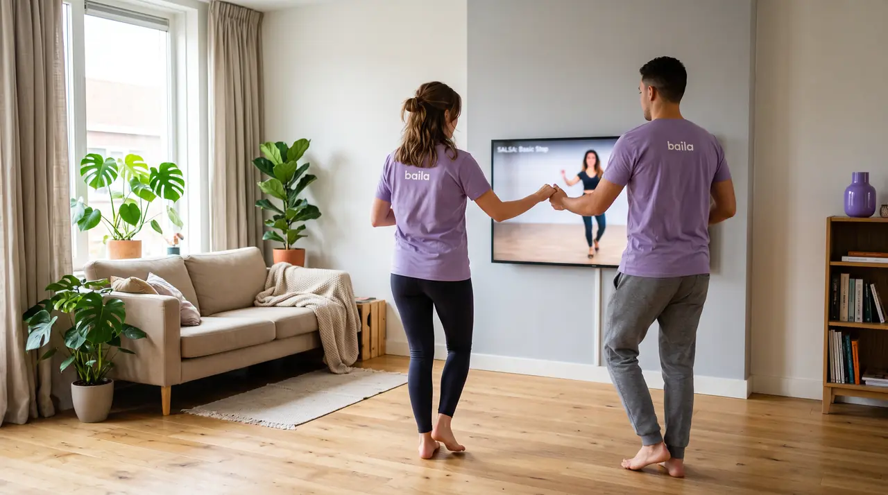 Een stel in paarse Baila-shirts oefent salsa in de woonkamer, met een instructievideo op de tv.